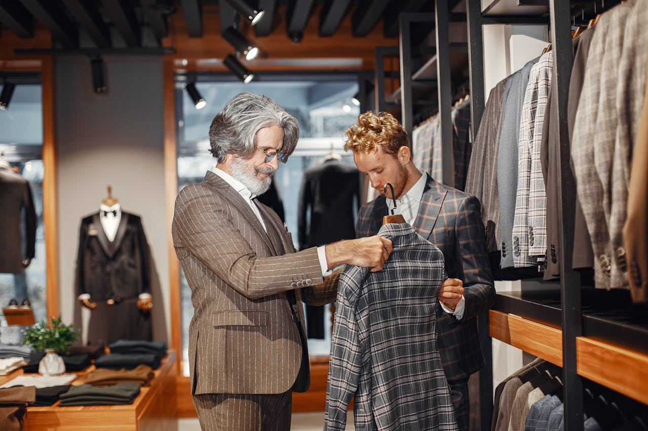 Home Two men choosing a suit in a stylish clothing boutique. Indoor shopping scene.